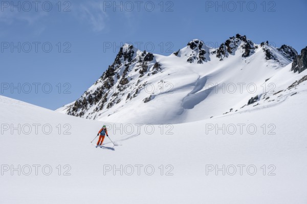 Ski tourer on the descent, minimalist winter landscape, white snow and dark mountains on the Scalettahorn, Graubünden, Switzerland, Europe