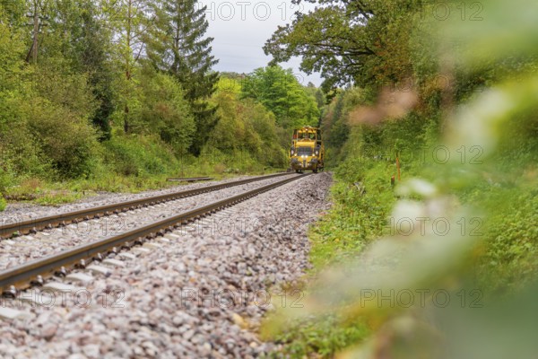 Yellow train runs on the rails through a green and autumnal landscape, tamping machine, Hermann Hessebahn, Althengstett, Black Forest, Germany, Europe