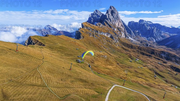 Paraglider over alpine meadows, in the background the peaks Sas Rigais and Furchetta of the Odle group, drone shot, Val Gardena, Dolomites, Autonomous Province of Bolzano, South Tyrol, Italy, Europe