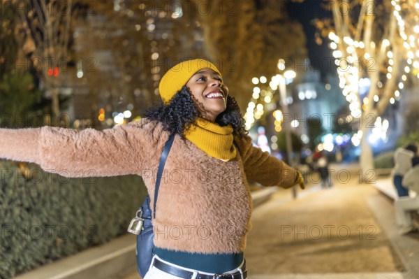 Young woman embracing the festive spirit of christmas lights while enjoying a winter evening in the city, radiating joy and happiness