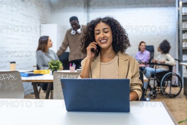 Cheerful woman talking to the mobile phone while working in a coworking space