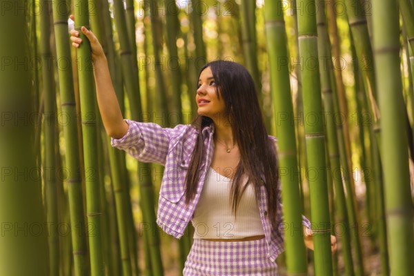 Young caucasian girl with a pink skirt in a bamboo forest. Enjoying summer holidays in a tropical climate, lifestyle of a girl walking and smiling in the forest