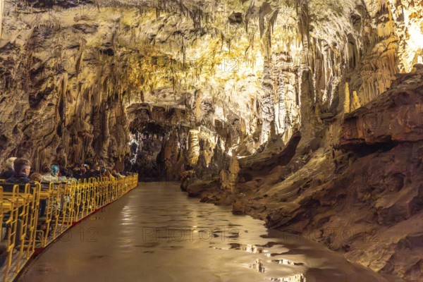 Tourists visiting the magnificent postojna cave in slovenia, riding an electric train through illuminated stalactites and stalagmites