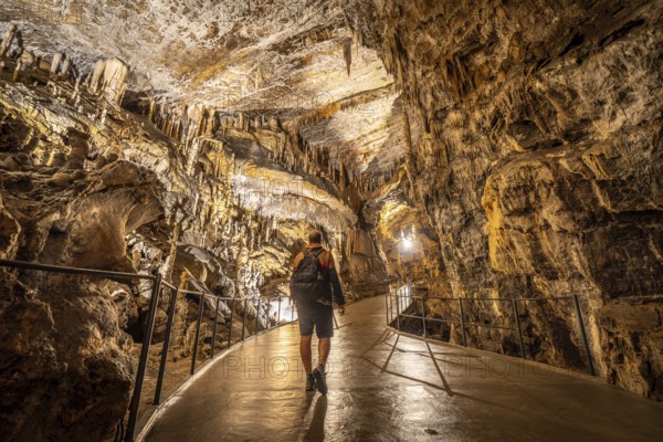 Tourist exploring postojna cave, a renowned natural wonder in slovenia, marveling at the stunning stalactite formations