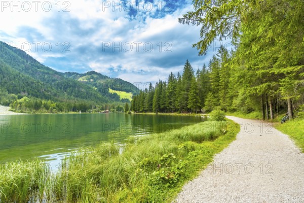 Emerald green waters reflecting the surrounding mountains and lush vegetation, creating a picturesque scene of tranquility in the heart of the dolomites