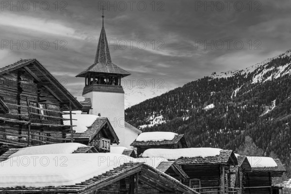 Old wooden houses with snow-covered roofs and the Saint Theodule church in the historic village centre, black and white photograph, Grimentz, Val d'Anniviers, Valais Alps, Canton Valais, Switzerland, Europe