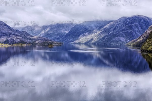 Fascinating landscape with mountains in the south of Chile, reflecting clouds on the surface of the sea create a peaceful atmosphere, Chile, South America