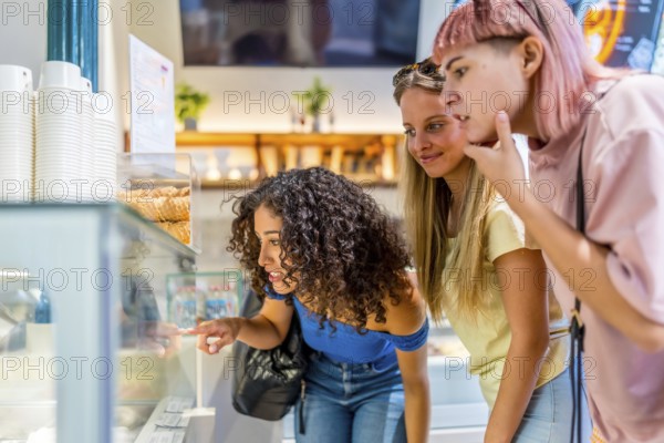Side view close-up with copy space of three diverse women choosing an ice cream in a mall