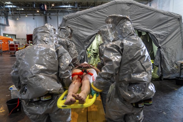 Decontamination of injured persons after an assumed accident involving hazardous substances, fire brigade and aid organisations practise setting up and operating a decontamination station, injured persons are sighted and then washed in a special shower tent to remove possible hazardous substances and chemicals in order to avoid further injuries, the emergency services wear special, ventilated protective suits, large-scale exercise by the Essen fire brigade