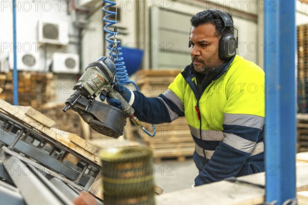 Man caucasian adult, worker in protective work gear recycling pallets in a factory of a recycling plant