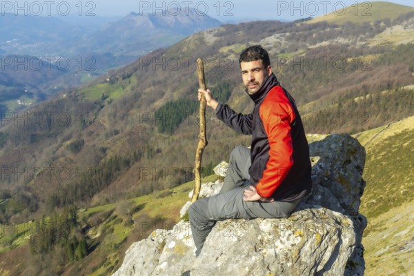 A man sitting on a rock at the top of Mount Ernio or Hernio in Gipuzkoa at sunset, Basque Country