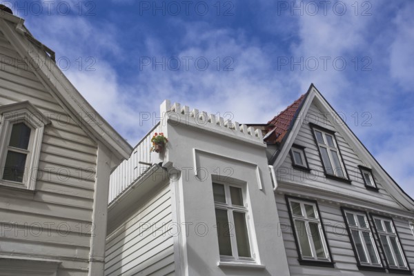 View upwards to white wooden houses with striking architecture under a clear blue sky, Bergen, Norway, Europe