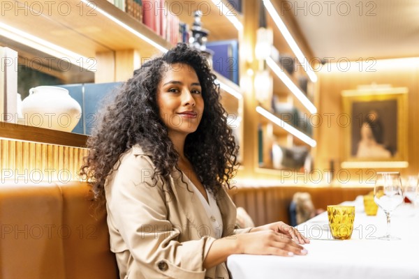 Side view portrait of a beauty latin woman sitting alone in a restaurant