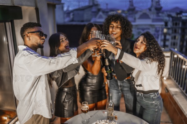 Top view of diverse and happy elegant multi-ethnic friends toasting with champagne during roof night party