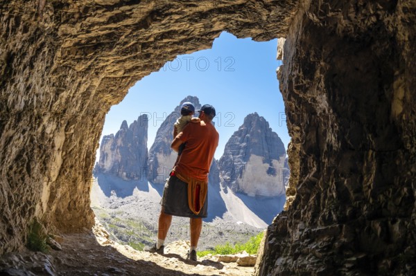 Father holding his son admiring the tre cime di lavaredo, dolomites, from a Tre Cime Cave during a summer hike