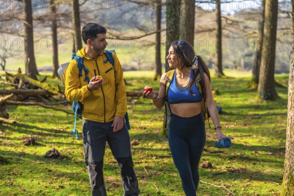 Hikers enjoying a healthy snack of apples while walking through a sunny forest during their outdoor adventure