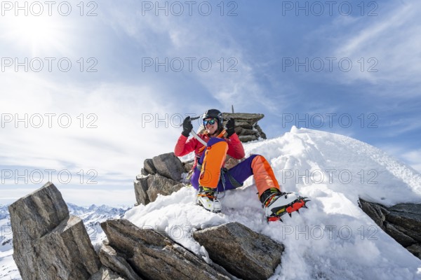Happy mountaineer with ice axes and crampons on the summit of Piz Grialetsch in winter, Graubünden Haute Route, Albula Alps, Rhaetian Alps, Graubünden, Switzerland, Europe