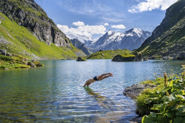 Man taking a header, cooling off while swimming in the mountain lake Lac de Louvie, behind the summit of the Grand Combin, Val de Bagnes, Valais, Switzerland, Europe