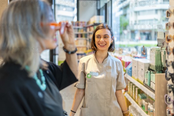 Young happy female ophthalmologist smiles and approves the glasses that a client is trying on