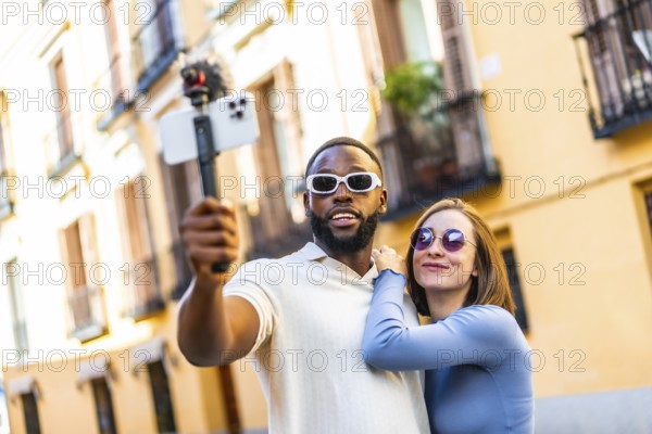 Multi-ethnic couple influencer vlogging from a travel destination standing in the city street