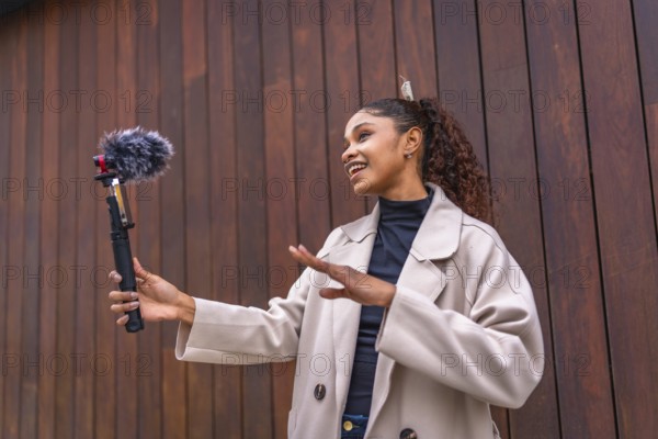 African american beauty woman vlogger talking to her audience streaming online next to wooden city wall