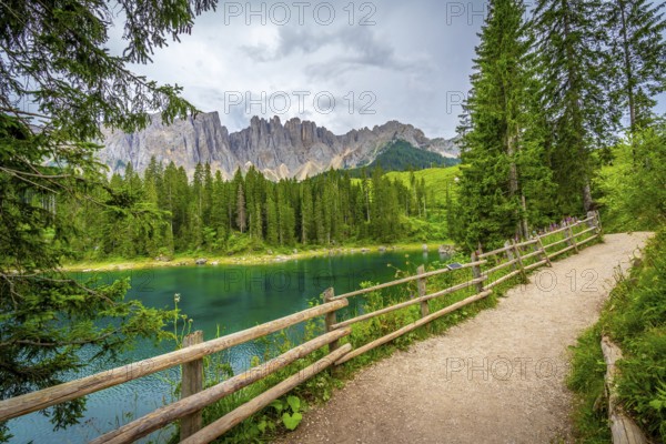 Emerald green water reflecting the majestic dolomites under a cloudy summer sky in south tyrol, italy, creates a serene landscape
