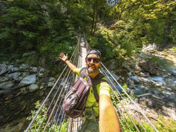 Hiker taking selfie while crossing hanging bridge over tolmin gorge in triglav national park, slovenia