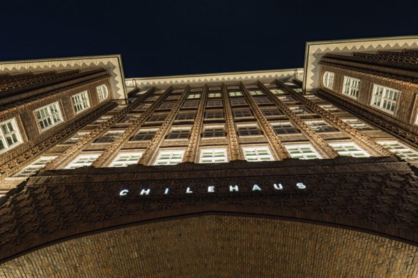 Symmetrical inner courtyard of a Kontorhaus at night, rows of windows and brick façade illuminated, Hamburg, Germany, Europe