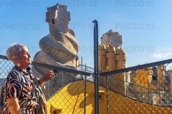 Senior tourist admiring the whimsical chimneys and vibrant architecture of casa mila, a unesco world heritage site in barcelona