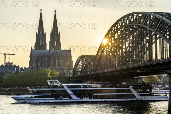 Silhouettes of the cathedral in late sunlight, freighter on the Rhine, view of Cologne Cathedral and the Hohenzollern railway bridge over the Rhine near Cologne, North Rhine-Westphalia, Germany, Europe