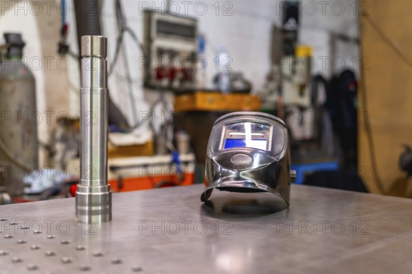 A welding helmet on a factory table with no people