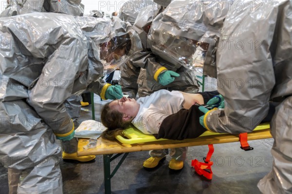 Decontamination of injured persons after an assumed accident involving hazardous substances, fire brigade and aid organisations practise setting up and operating a decontamination station, injured persons are sighted and then washed in a special shower tent to remove possible hazardous substances and chemicals in order to avoid further injuries, the emergency services wear special, ventilated protective suits, large-scale exercise by the Essen fire brigade
