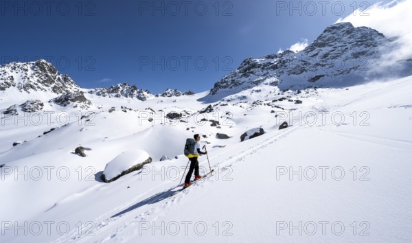 Ski tourers ascending through picturesque snow-covered mountain landscape with Piz Kesch summit, ascent to Kesch Pitschen summit, Bündner Haute Route ski tour, Albula Alps, Rhaetian Alps, Grisons, Eastern Switzerland, Switzerland, Europe