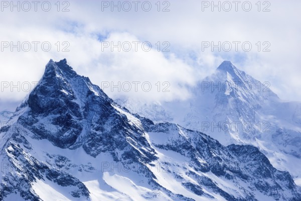 Wisps of mist surround the snow-covered peaks of the mountains Le Besso and Obergabelhorn, Val d'Anniviers, Valais Alps, Canton Valais, Switzerland, Europe