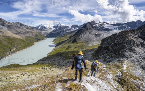 Two mountaineers on the summit of Mont de la Blana, view of a blue mountain lake, Lac des Dix reservoir, mountain peak Mont Blanc de Cheilon with glacier in the background, Hérménence, Valais Alps, Valais, Switzerland, Europe