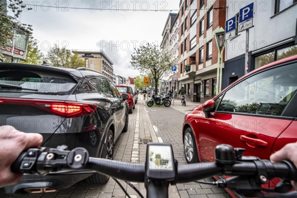 Cycling in the city, inner-city street, cycle lane, bicycles have priority, two-lane traffic with parked cars on both sides, cyclists' perspective, Essen, North Rhine-Westphalia, Germany, Europe