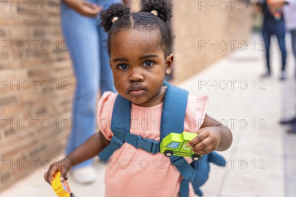 Close-up of an african cute schoolgirl carrying card toys in the street