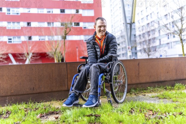 Young man with disability smiling in his wheelchair enjoying a day out in an urban park, promoting inclusivity and accessibility