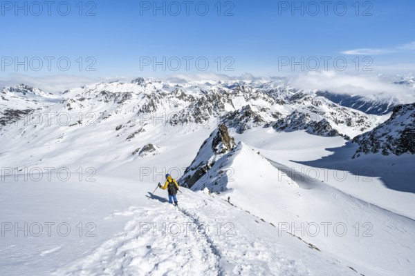 Mountaineer with ice axe and crampons, descent through steep snowfield on Piz Kesch or Piz d'Es-cha in winter, view of mountain panorama with Vadret da Porchabella glacier, Albula Alps, Rhaetian Alps, Grisons, Eastern Switzerland, Switzerland, Europe