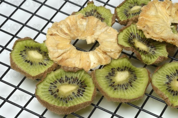 Dried pineapple slices and dried kiwi slices on a wire rack