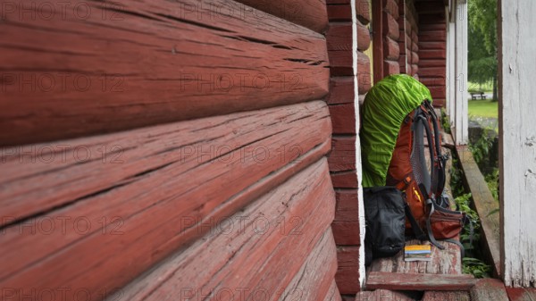 A pilgrim's rucksack standing against a wooden shed painted falun red, medieval church, pole, Norway, Europe