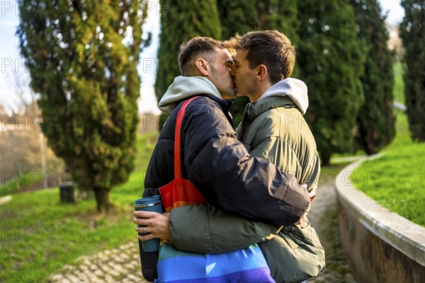 Two men are kissing in a park, embracing each other tenderly, showcasing their love and commitment
