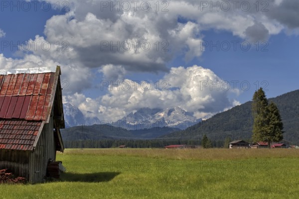 A peaceful alpine landscape with meadows, an old barn and mountains in the background, Wallgau, Bavaria, Germany, Europe