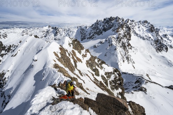 Mountaineer belaying on a steep snow slope, belaying on a rope, ascent to the summit of Piz Grialetsch in winter, view of mountain panorama with Piz Vadret with snow, Grisons Haute Route, Albula Alps, Rhaetian Alps, Grisons, Switzerland, Europe