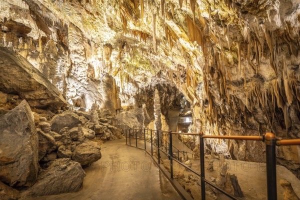 Tourists visiting the famous postojna cave, located in slovenia, walking on illuminated cemented path among stalactites and stalagmites