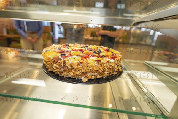 An artistically decorated cake with almond slivers and fruit in a glass display case, Cafe Kuh, Deckenpfronn, Germany, Europe