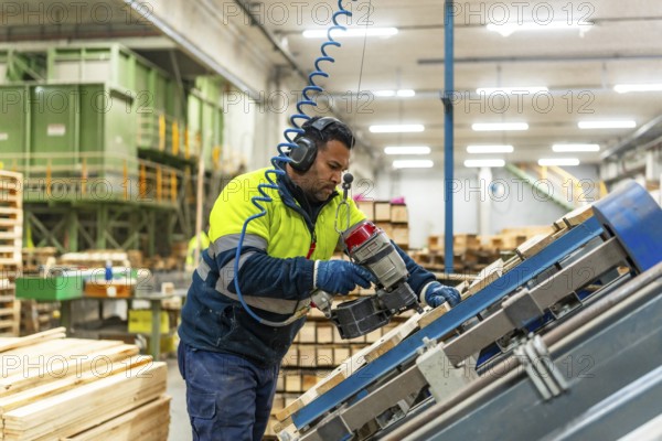 Side view three quarter length photo of a caucasian man worker arranging pallets to reuse it in a recycling plant factory