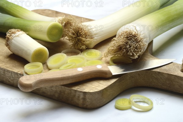 Leek, leek sticks and leek rings on a chopping board with a knife