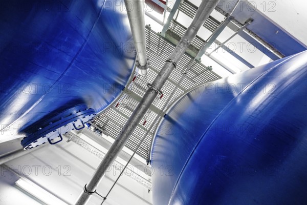 View between two large blue metal tanks with a grid attached to the top, ENCW Netze Calw waterworks, Calw, Black Forest, Germany, Europe