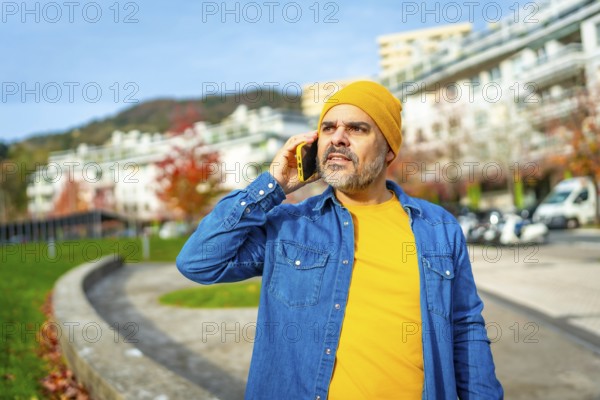 Modern mature man talking to the mobile walking down the street